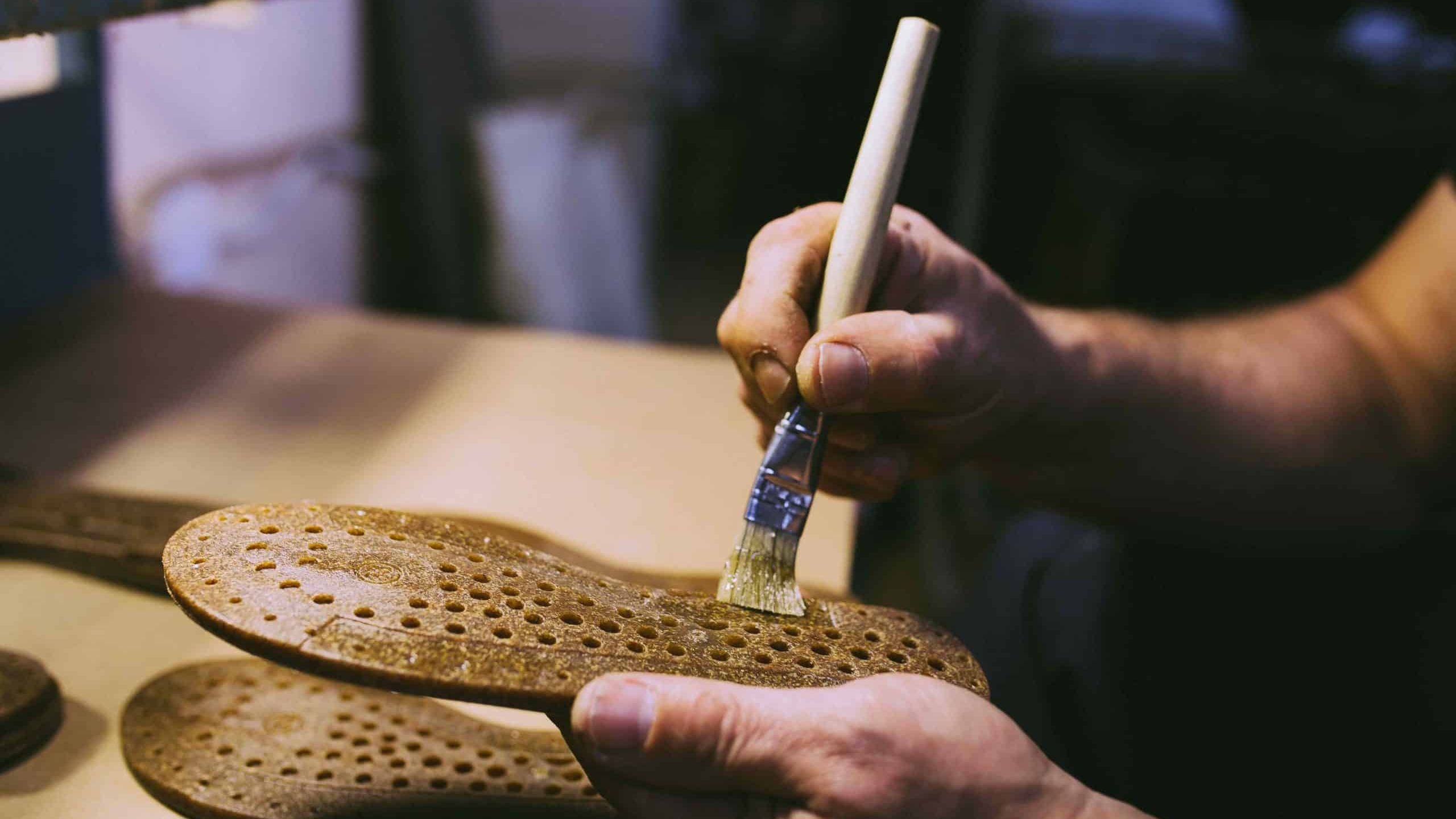 Shoemaker applying glue to a leather shoe sole