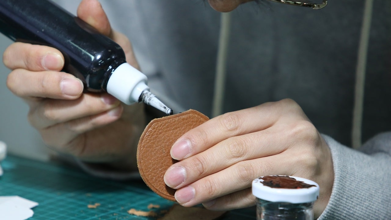 Artisan qui réalise un encollage du cuir